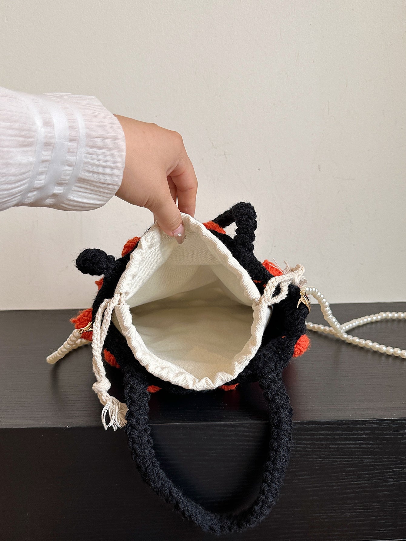 Black and orange handmade woven handbag with pearl decoration.