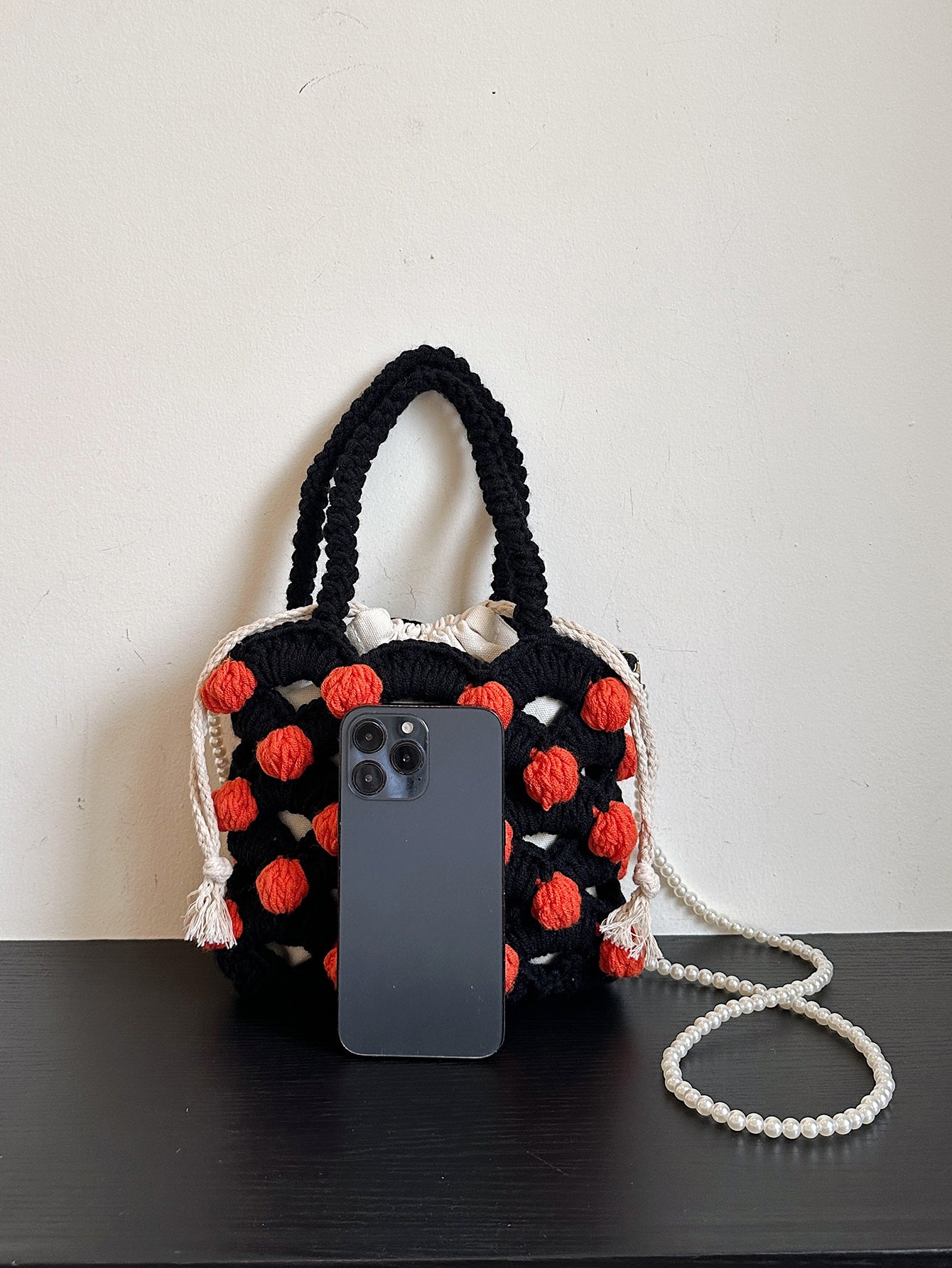 Black and orange handmade woven handbag with pearl decoration.