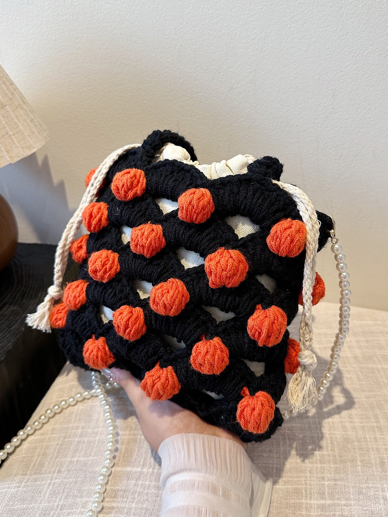 Black and orange handmade woven handbag with pearl decoration.