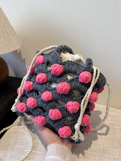 Handwoven tote bag with a gray woven base and pink circular accents, adorned with pearl chain details. Unique design, perfect for daily use or shopping.