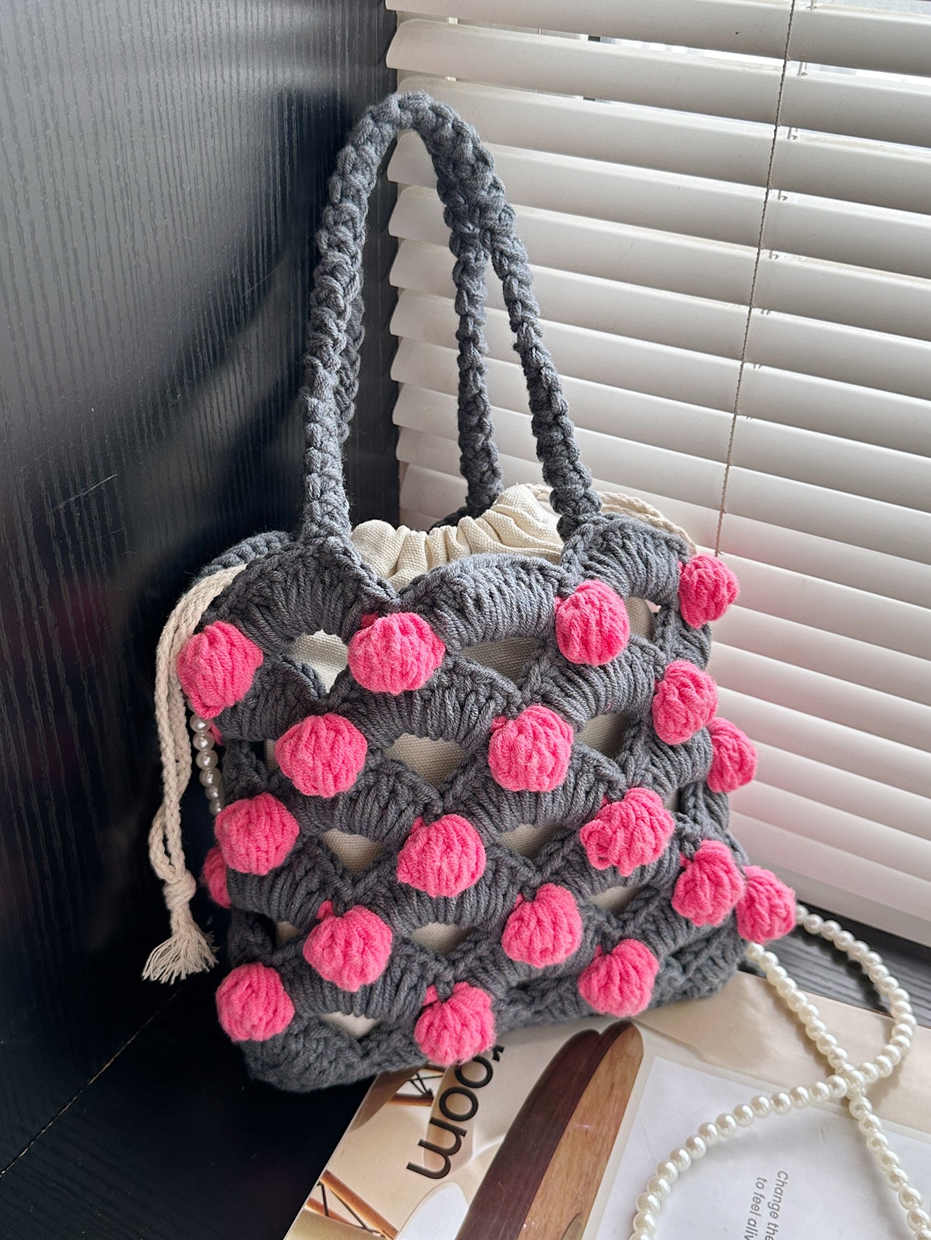 Handwoven tote bag with a gray woven base and pink circular accents, adorned with pearl chain details. Unique design, perfect for daily use or shopping.