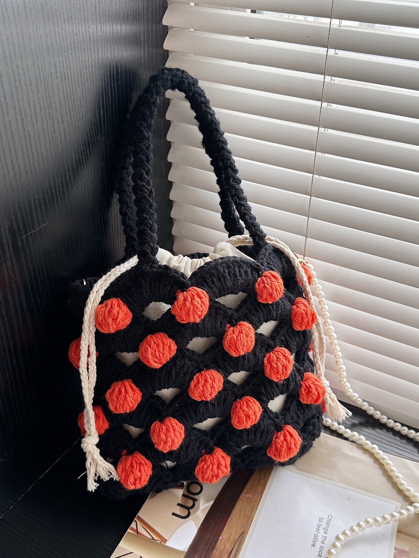 Black and orange handmade woven handbag with pearl decoration.

