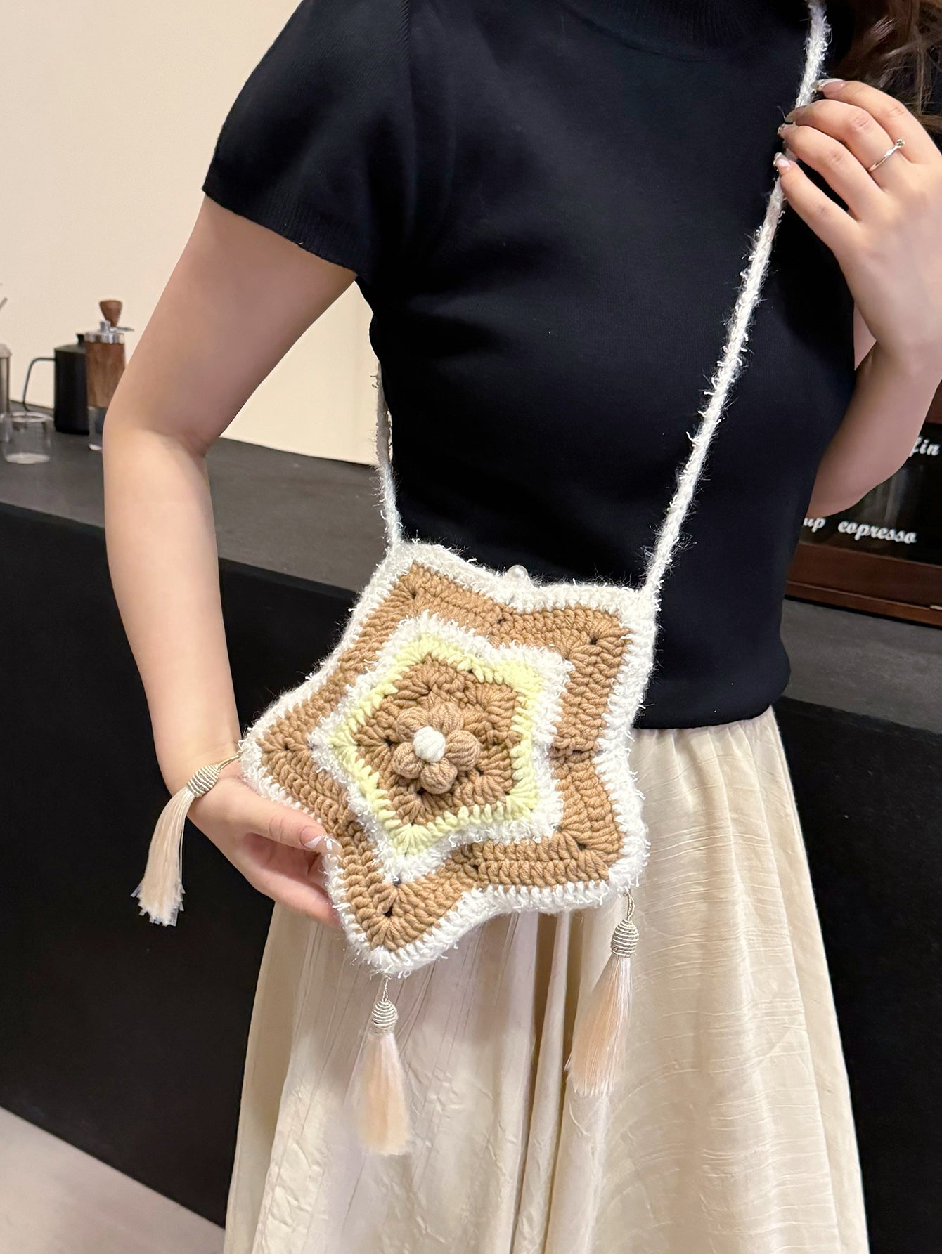 Handwoven star-shaped knit bag with soft knit material, tassel accents, and a mix of brown, white, and yellow colors, perfect for daily use or decoration.