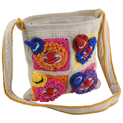 Handmade crochet shoulder bag with colorful 3D clown face patterns, featuring a beige base and vibrant multicolored details. Lightweight, artistic, and perfect for casual outings or as a unique gift.