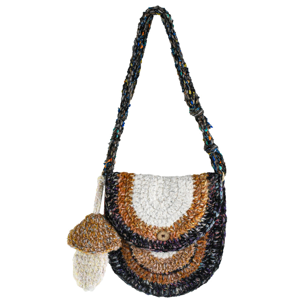 Handmade crochet crossbody bag with earthy tones, featuring a unique mushroom charm, semi-circle flap design, and durable woven strap. Lightweight and eco-friendly, perfect for boho and vintage-inspired styles.