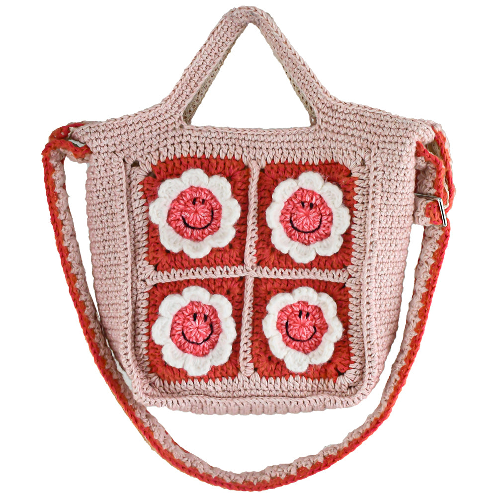 Handmade pink crochet bag with red and white floral square patterns, featuring a top handle. Perfect for casual outings or shopping