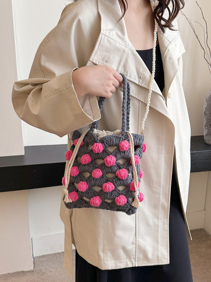 Handwoven tote bag with a gray woven base and pink circular accents, adorned with pearl chain details. Unique design, perfect for daily use or shopping.