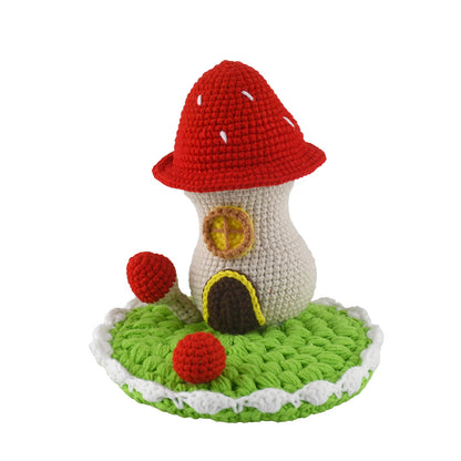 Decorative crochet toadstool cottage featuring bright red cap with white dots, beige body, and green circular base
