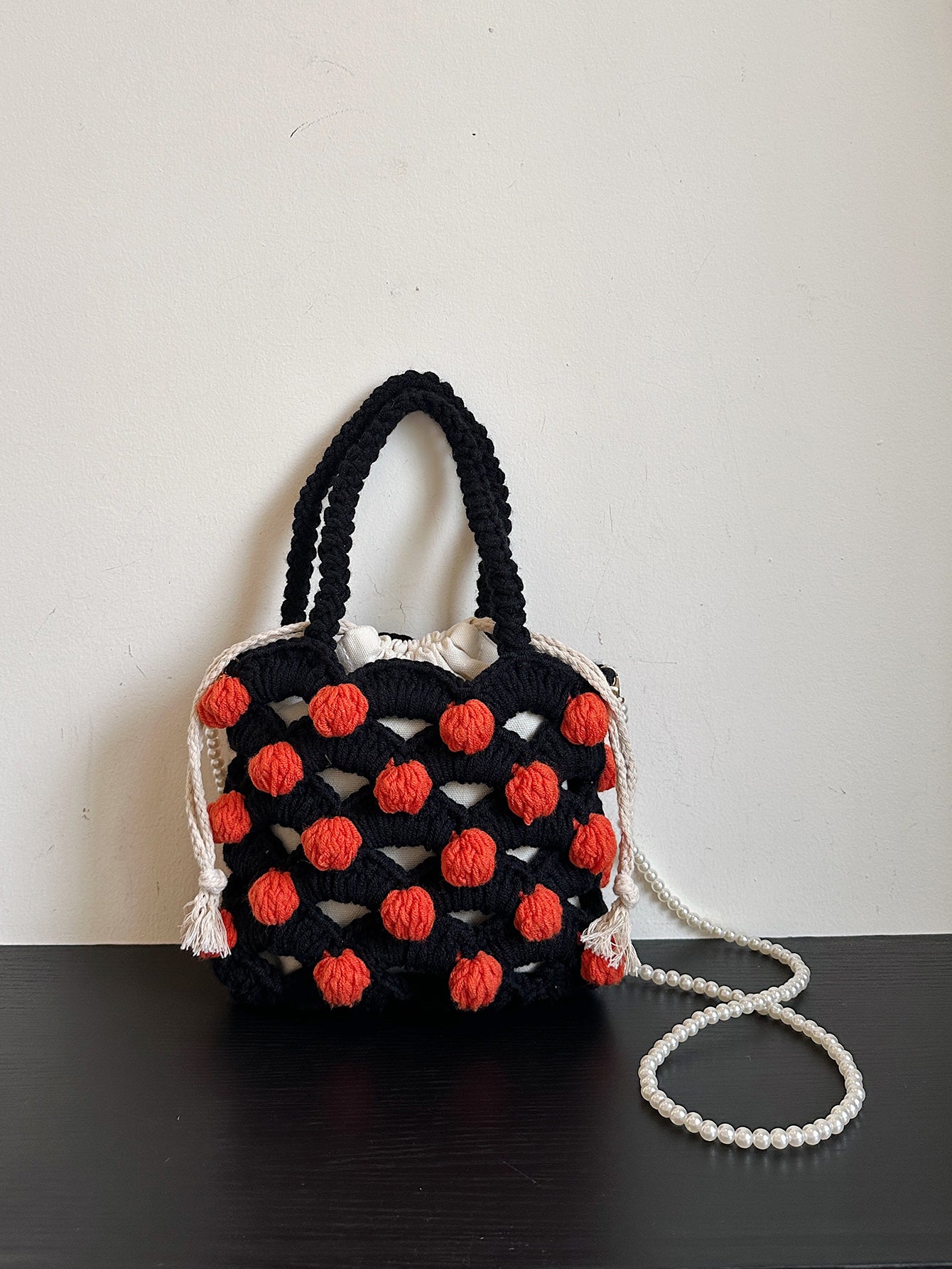 Black and orange handmade woven handbag with pearl decoration.

