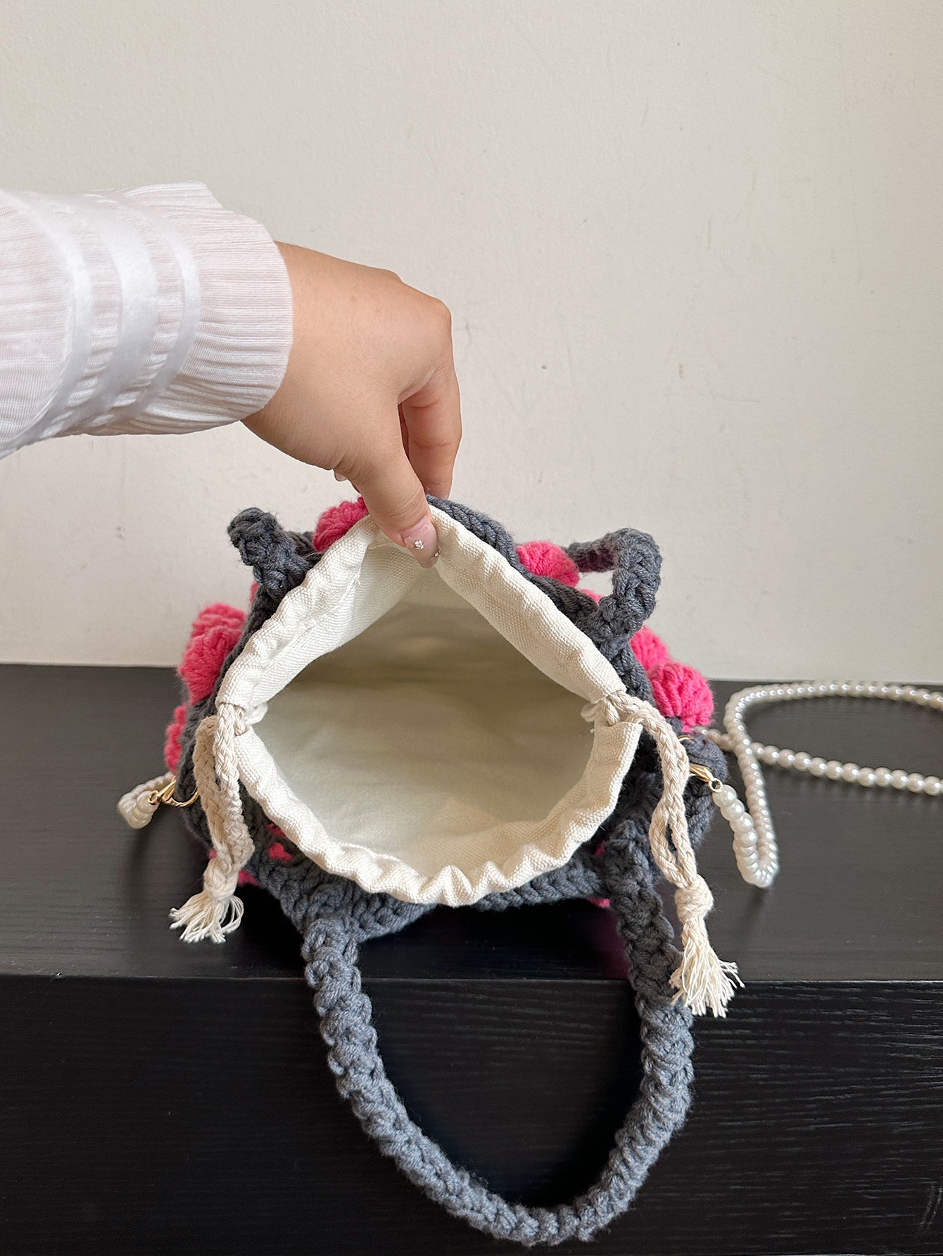 Handwoven tote bag with a gray woven base and pink circular accents, adorned with pearl chain details. Unique design, perfect for daily use or shopping.