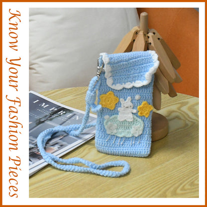 Handmade crochet phone crossbody bag in baby blue with white bunny on mint cloud applique and yellow stars, featuring scalloped white trim and braided strap
