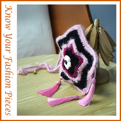 Handmade star-shaped crochet bag in pink and black with three pink tassels, white flower center, and braided shoulder strap
