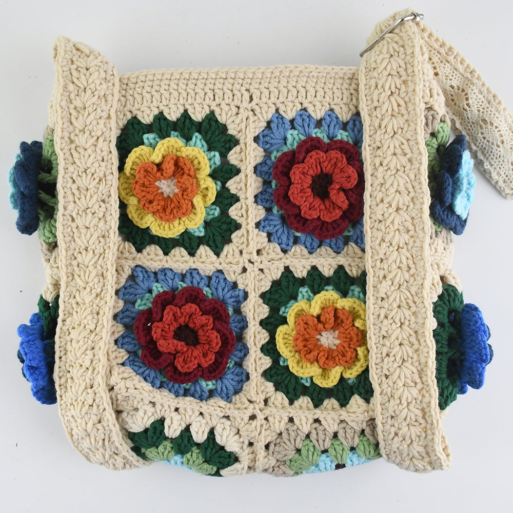 Handmade crochet tote bag featuring a colorful 3D floral design. Beige base with red, blue, green, and yellow flower accents. Lightweight, spacious, and perfect for shopping or casual outings.