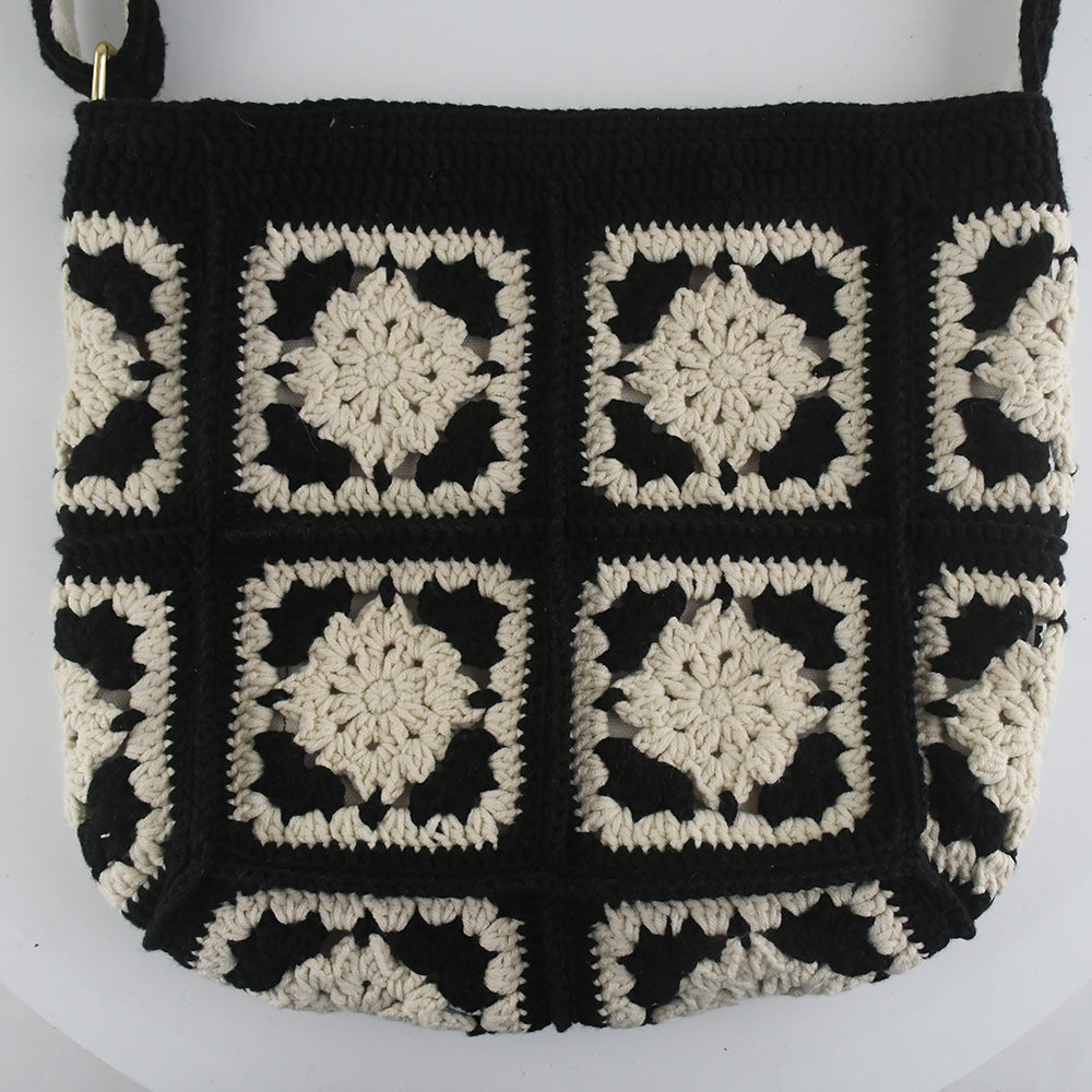 Handmade crochet crossbody bag with a black and white patchwork design, featuring square floral patterns, an adjustable strap, and a soft, lightweight texture.