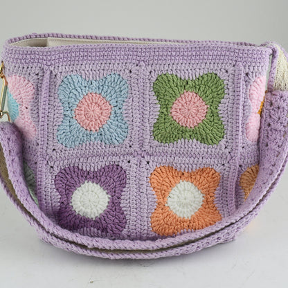 A handmade crochet shoulder bag with a lavender base and colorful floral square patterns. The bag features an adjustable and detachable strap, a soft texture, and a spacious interior, perfect for daily use or casual outings.