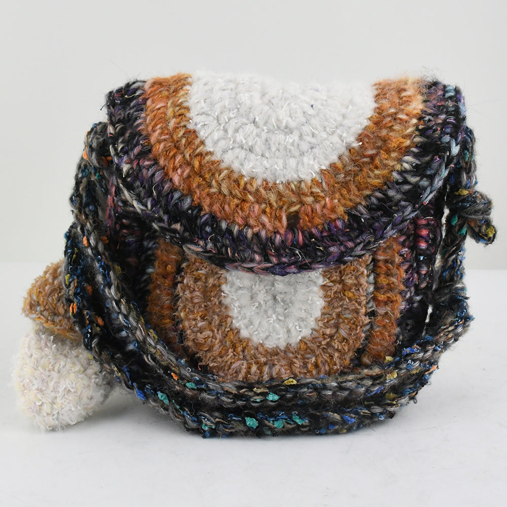 Handmade crochet crossbody bag with earthy tones, featuring a unique mushroom charm, semi-circle flap design, and durable woven strap. Lightweight and eco-friendly, perfect for boho and vintage-inspired styles.