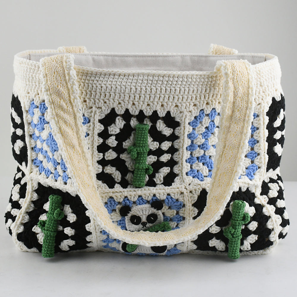 Handmade crochet tote bag featuring a panda design with bamboo patterns, blue and black square details, and a soft white base. Perfect for casual outings or eco-friendly shopping.