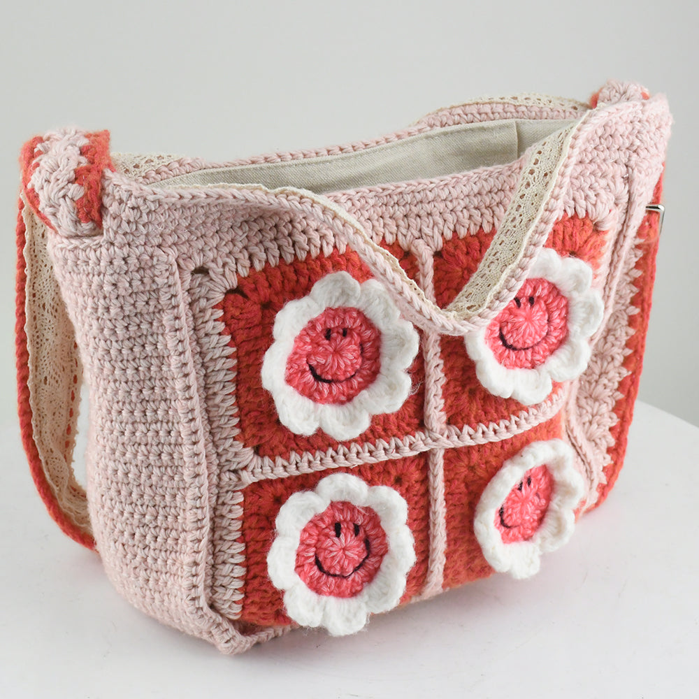 Handmade pink crochet bag with red and white floral square patterns, featuring a top handle. Perfect for casual outings or shopping