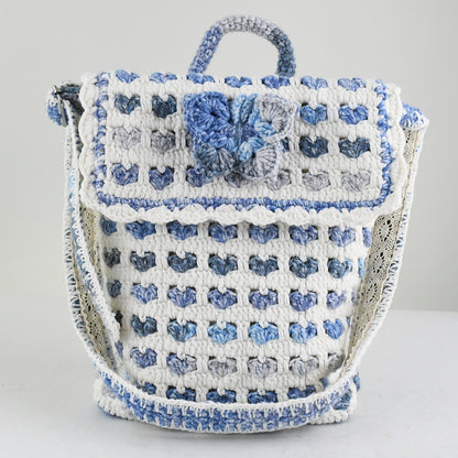 Handmade crochet shoulder bag with a unique blue and white floral pattern, featuring an adjustable strap and secure flap closure. Lightweight and perfect for everyday use.