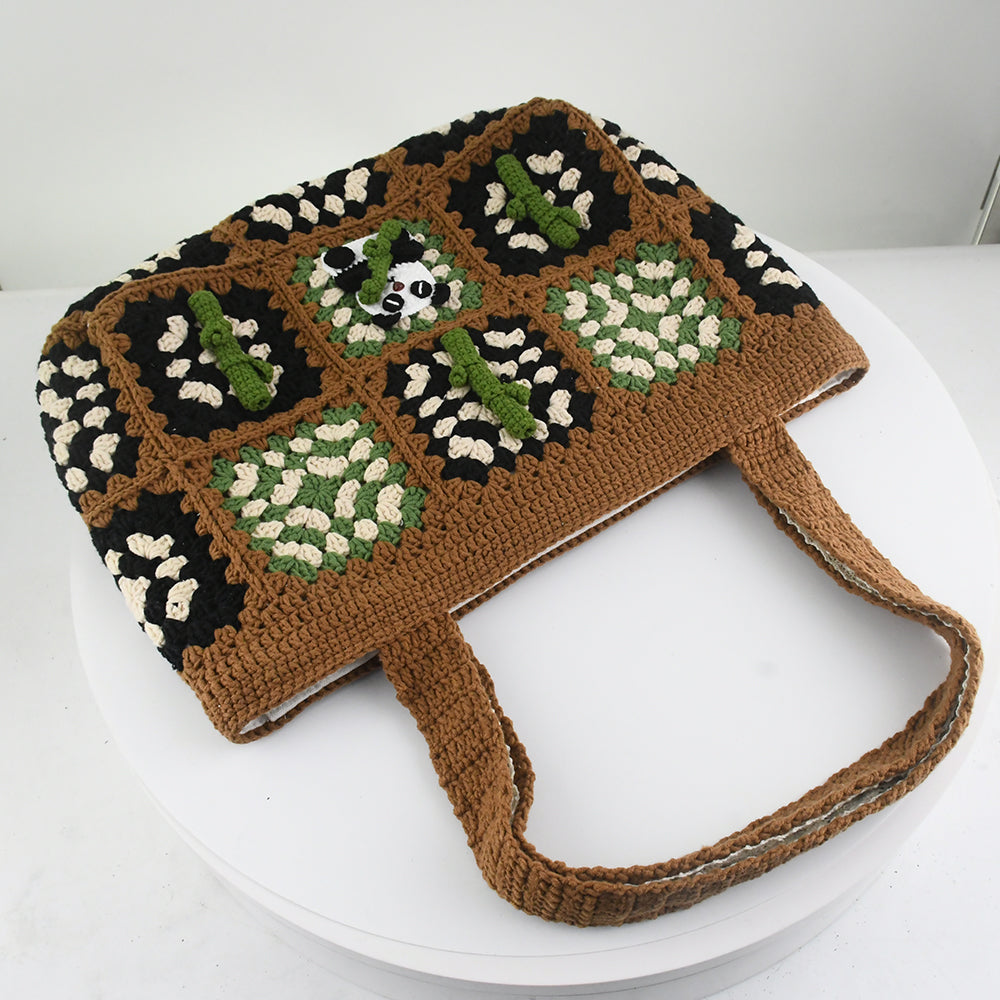 Handmade crochet patchwork bag with a brown base, black, green, and white patterns, featuring a panda and bamboo design in the center. Vintage style, eco-friendly, and lightweight, ideal for shopping or daily use.