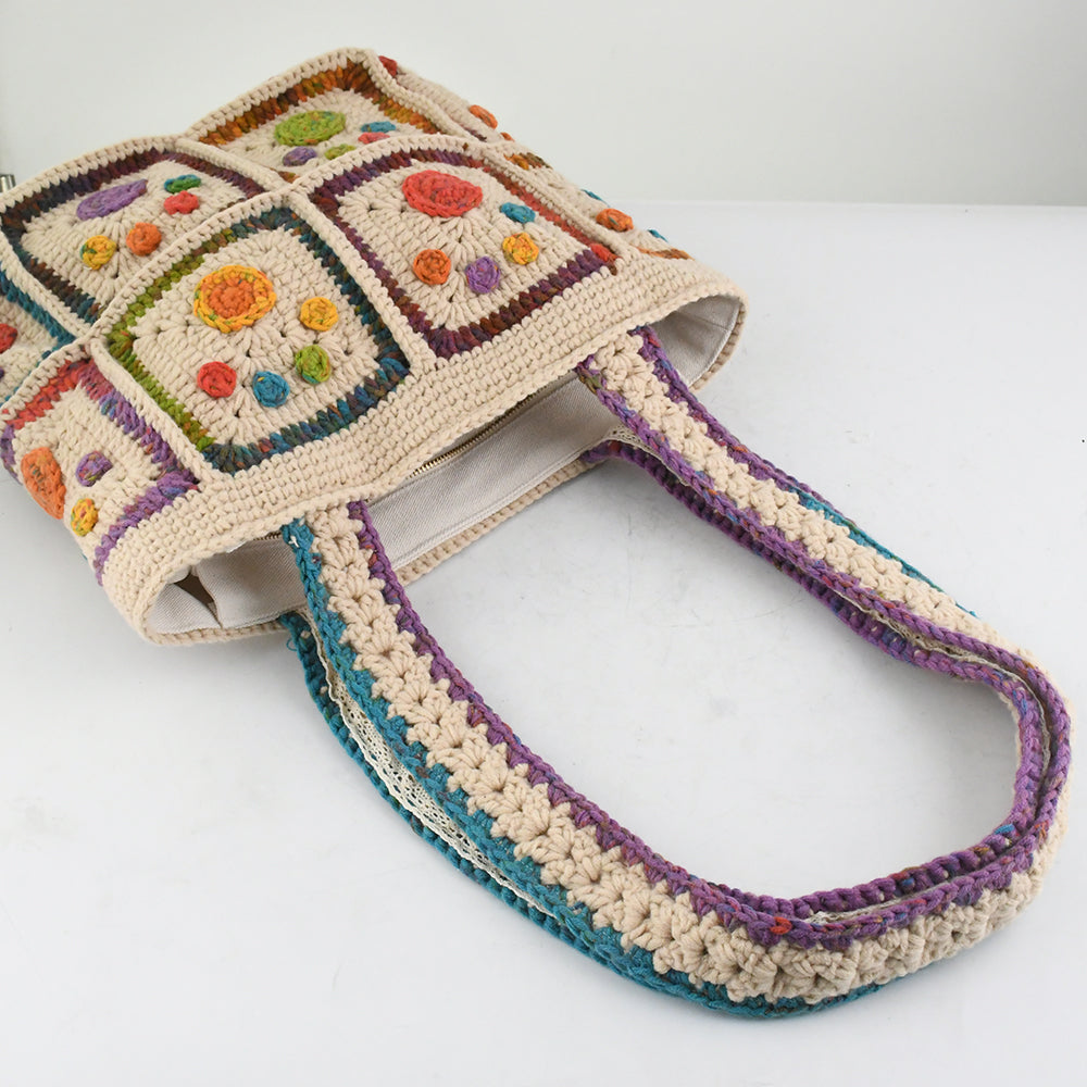 Handmade crochet tote bag with colorful floral and paw patterns, featuring a beige base and multicolor woven straps. Lightweight and spacious, perfect for casual outings or daily use.