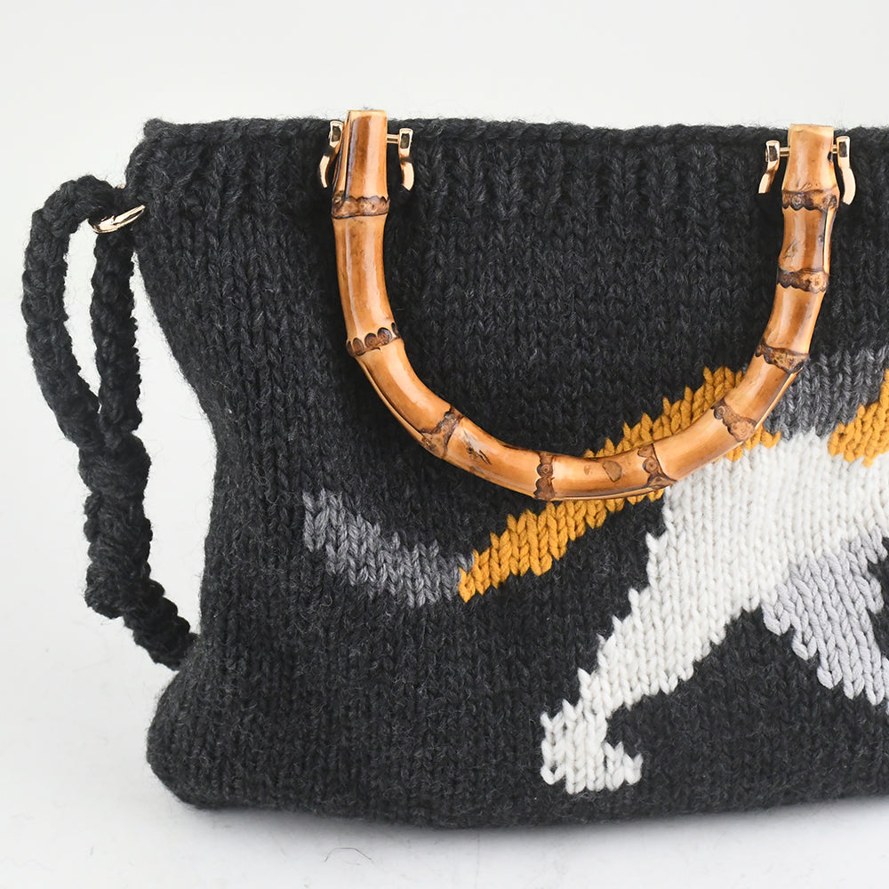 Handmade knitted black tote bag featuring a bamboo handle, embroidered cat design, and colorful floral accents. Lightweight and eco-friendly, perfect for casual or creative fashion styles.