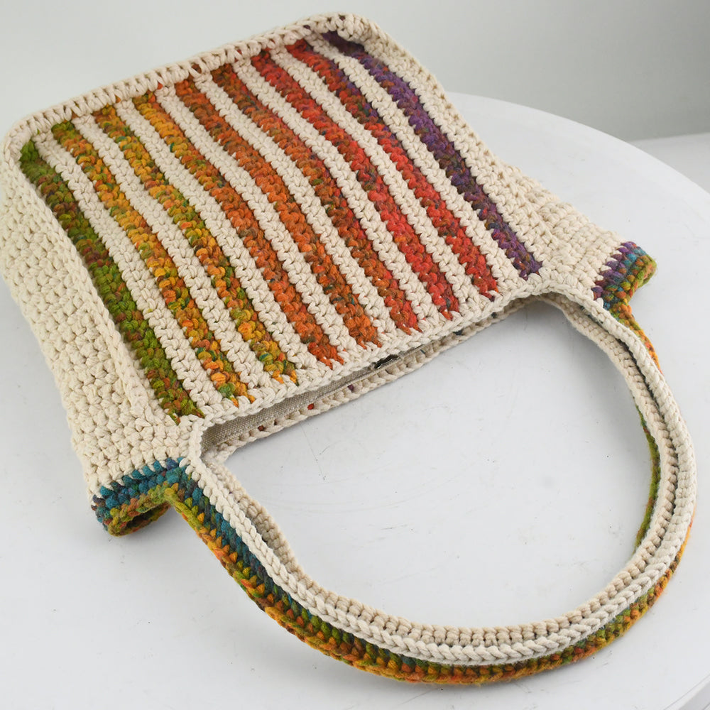 Handmade crochet tote bag featuring a natural cream base with colorful rainbow stripes. The bag has a spacious design with matching rainbow-accented shoulder straps, perfect for casual outings, shopping, or beach trips