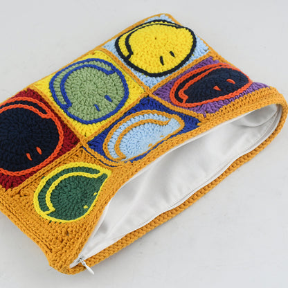 Handmade crochet clutch bag featuring colorful smiling face motifs in pink, yellow, blue, green, red, and orange squares. Lightweight, eco-friendly, and compact design with a secure zipper closure.