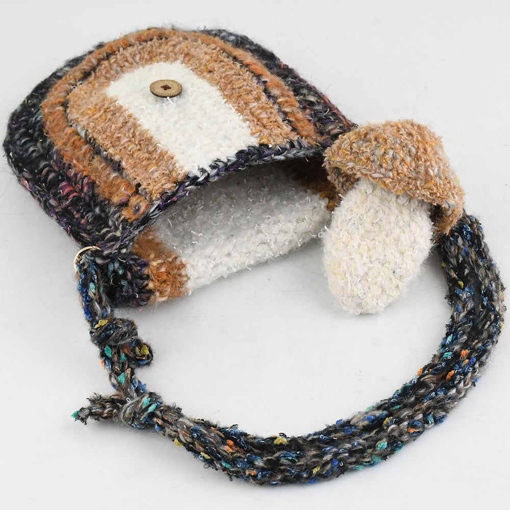 Handmade crochet crossbody bag with earthy tones, featuring a unique mushroom charm, semi-circle flap design, and durable woven strap. Lightweight and eco-friendly, perfect for boho and vintage-inspired styles.