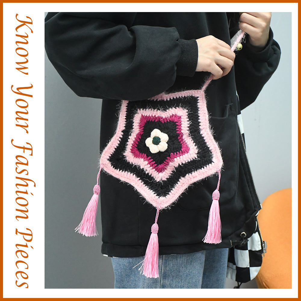 Handmade star-shaped crochet bag in pink and black with three pink tassels, white flower center, and braided shoulder strap
