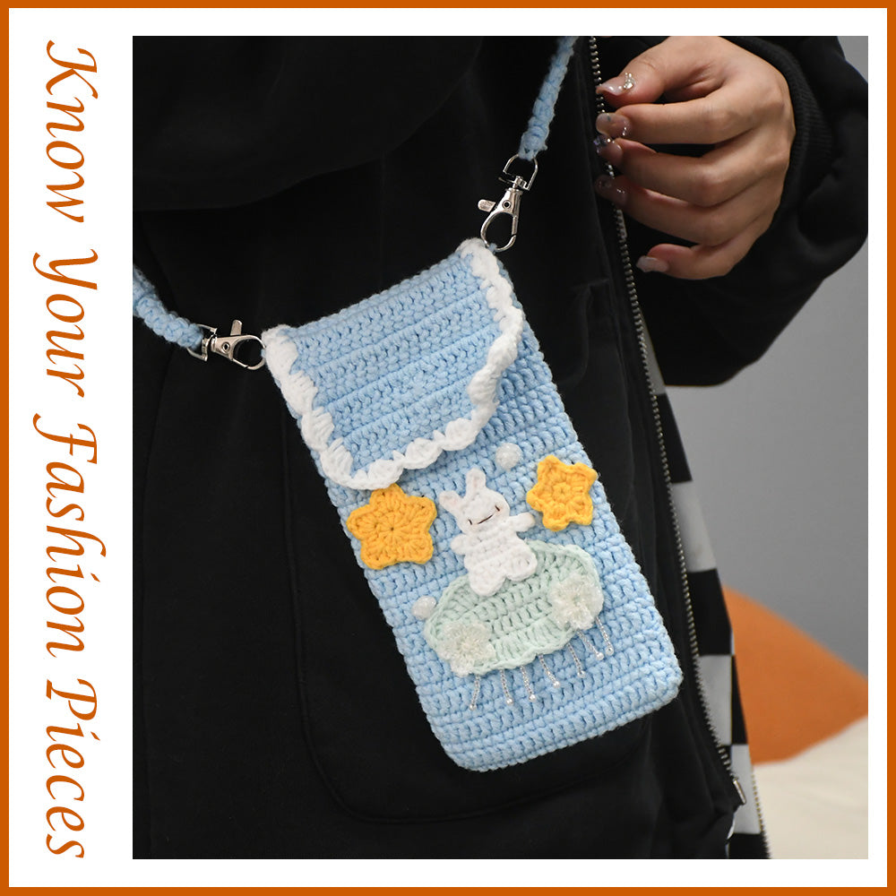 Handmade crochet phone crossbody bag in baby blue with white bunny on mint cloud applique and yellow stars, featuring scalloped white trim and braided strap
