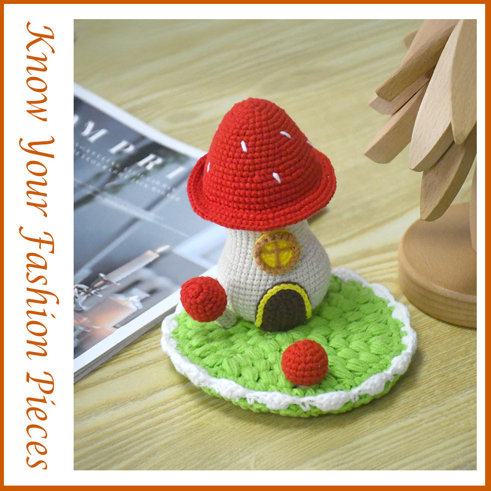 Decorative crochet toadstool cottage featuring bright red cap with white dots, beige body, and green circular base
