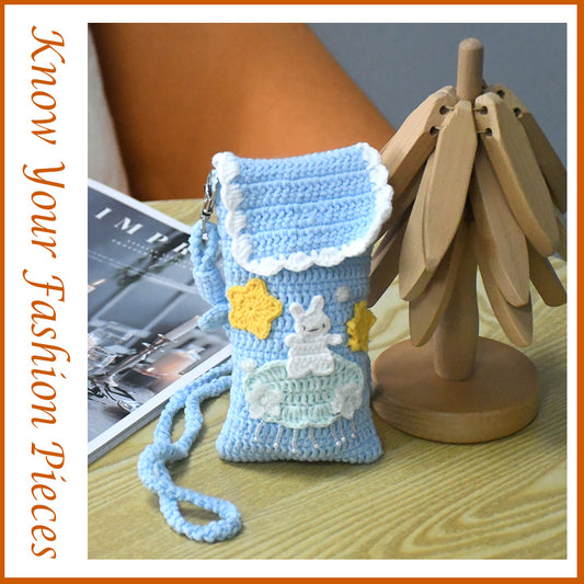 Handmade crochet phone crossbody bag in baby blue with white bunny on mint cloud applique and yellow stars, featuring scalloped white trim and braided strap
