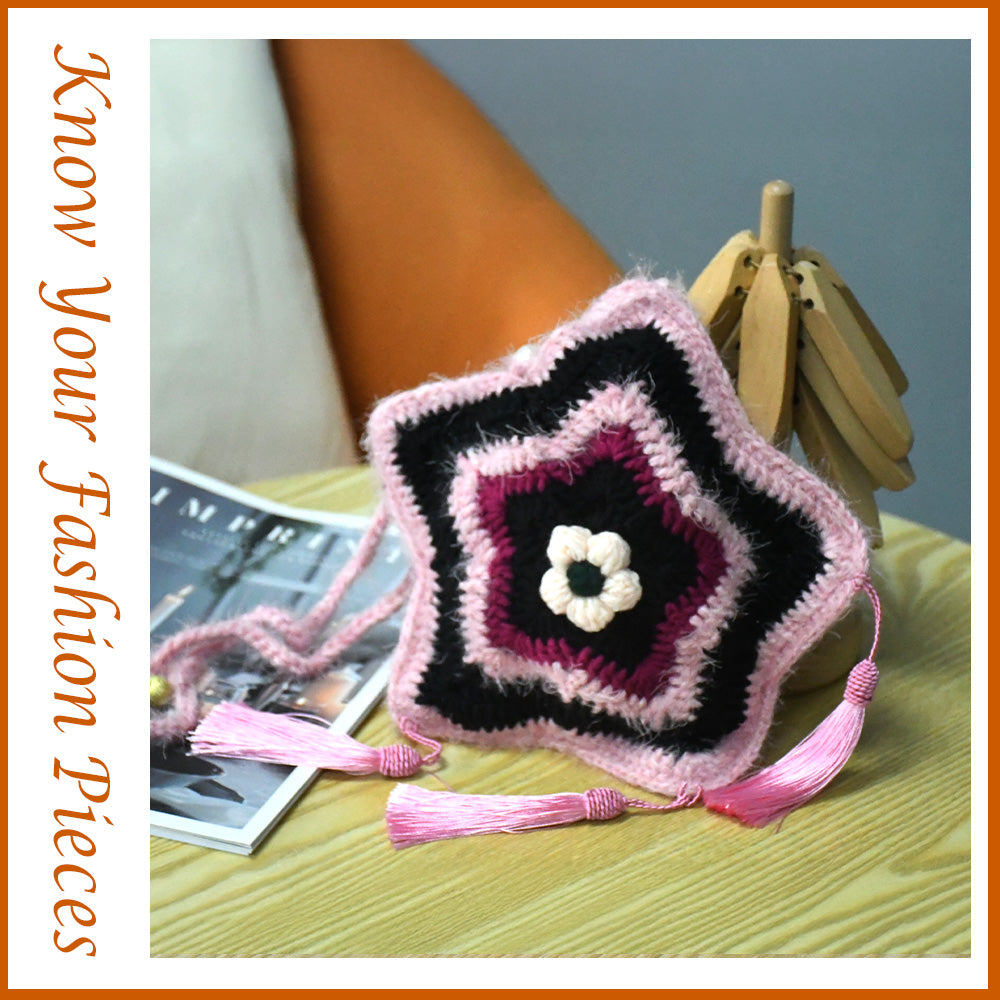 Handmade star-shaped crochet bag in pink and black with three pink tassels, white flower center, and braided shoulder strap
