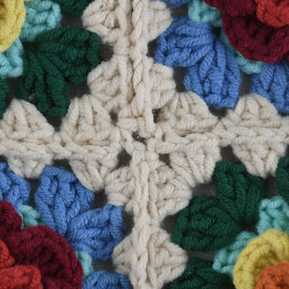 Handmade crochet tote bag featuring a colorful 3D floral design. Beige base with red, blue, green, and yellow flower accents. Lightweight, spacious, and perfect for shopping or casual outings.